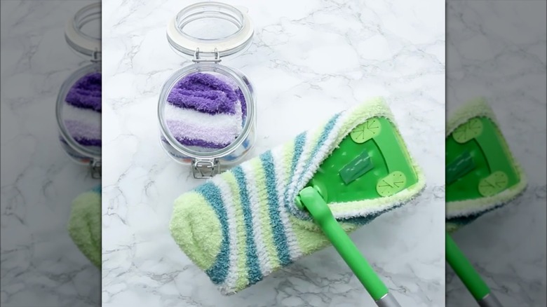 Swiffer mop with fuzzy sock on it, and a small jar of fuzzy socks next to it