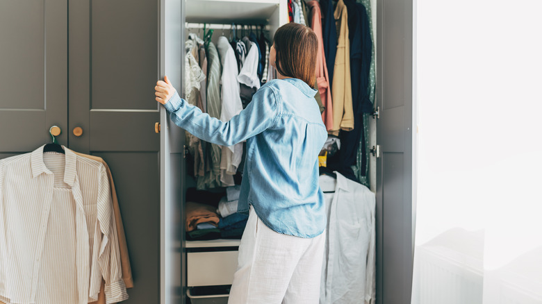 Woman opening small closet with shelves