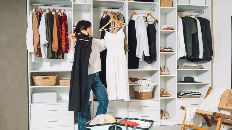 Woman holding dresses in front of custom closet with shelving