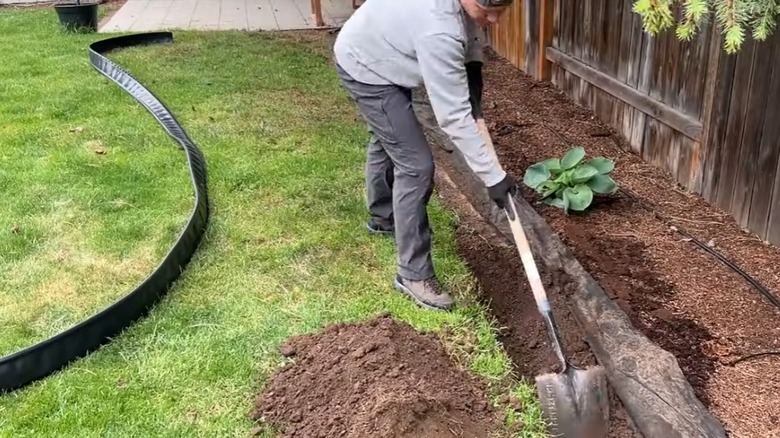 A person digging trench while uncoiled edging is warming behind them