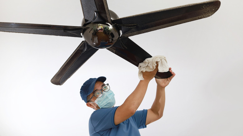 man cleaning his ceiling fan 
