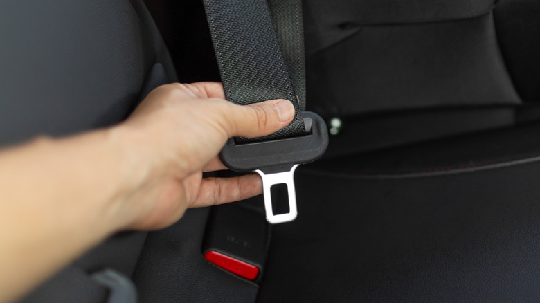 Man holding a car seat buckle in his hand