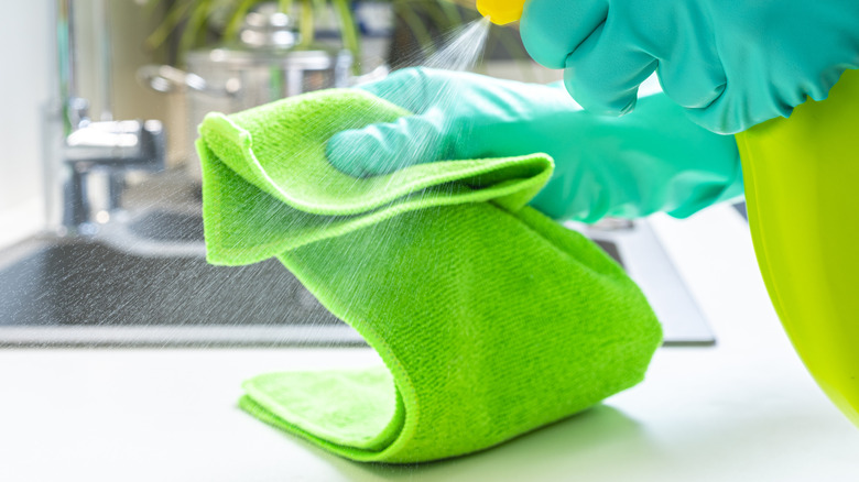 Microfibre towel being sprayed by someone wearing rubber gloves