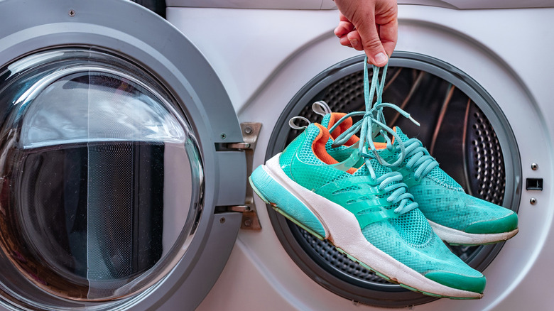 Hand holds sneakers in front of dryer