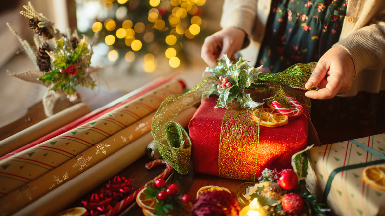 Hands wrapping Christmas gifts with themed paper