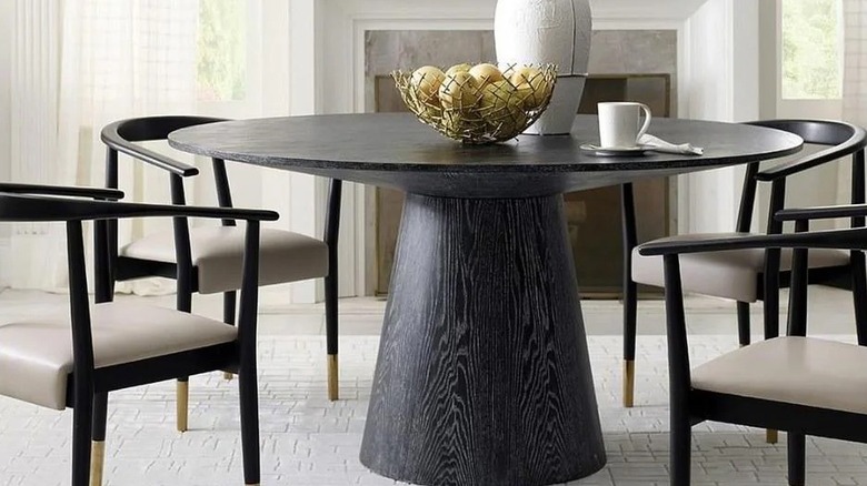 Round cerused black oak dining table in a dining room with leather wooden chairs