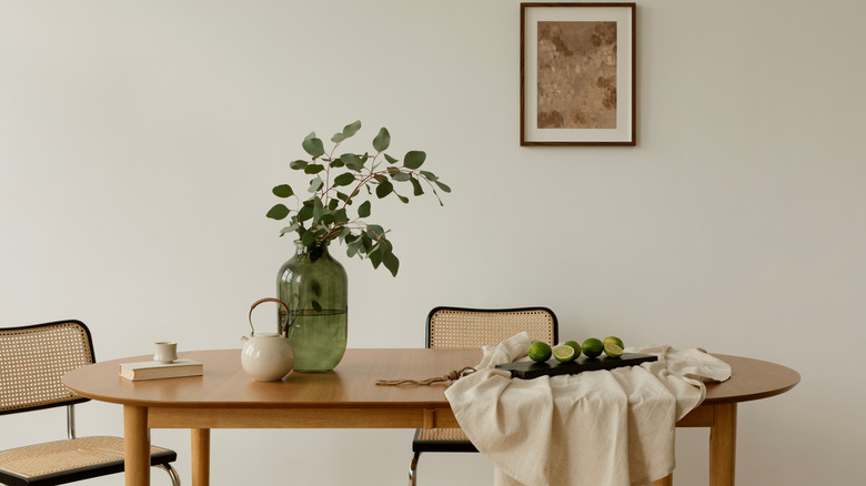 Bright interior with minimalist setup, a dining table styled with greenery, teapot, and limes on linen.