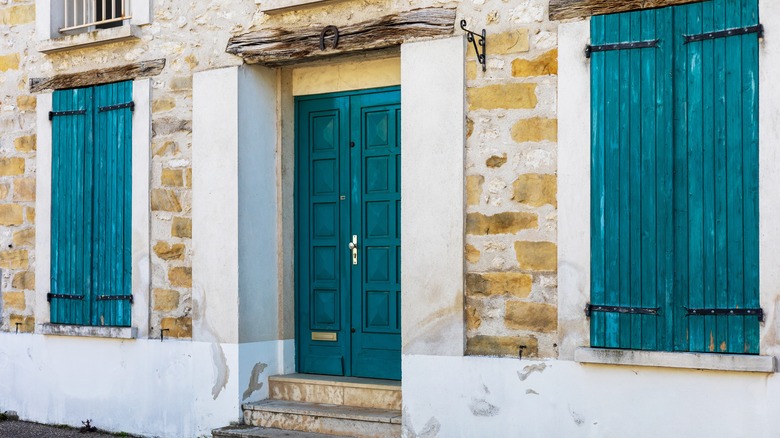 A stone exterior with a vibrant teal front door and matching shutters.