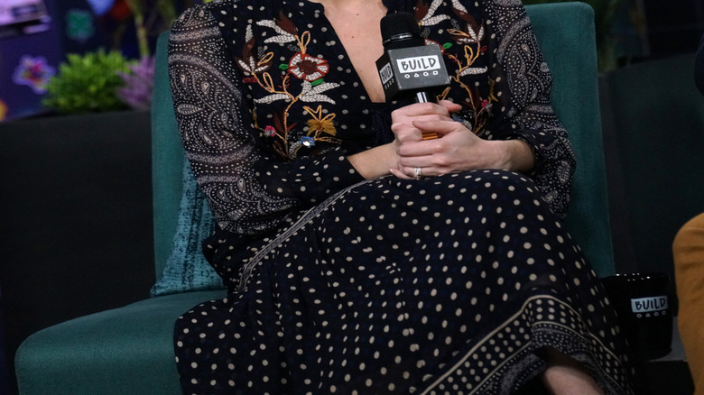 Erin Napier smiles while holding a microphone during an interview.