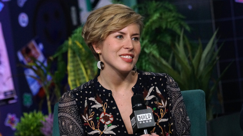 Erin Napier smiles while holding a microphone during an interview.