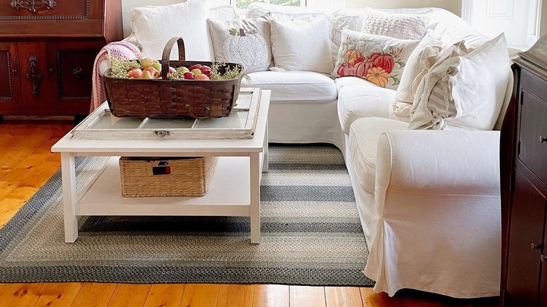 A cozy farmhouse living room with a soft braided rug and white sofa