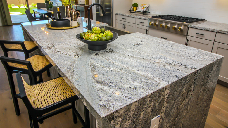 A kitchen island with a waterfall stone with grays, whites, and blacks with strong veining