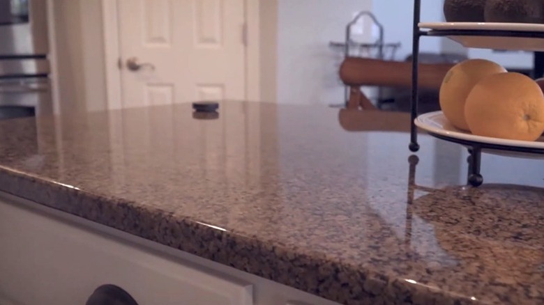 A woman with wiping down dated Baltic brown countertop with a sponge