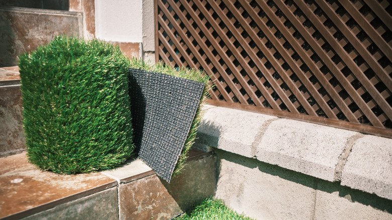 A roll of artificial grass is ready to install in a yard.