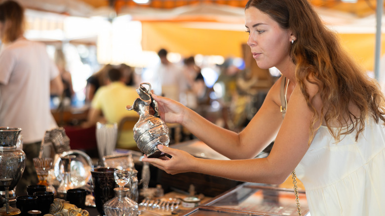 A woman holds an antique item at a thrift market