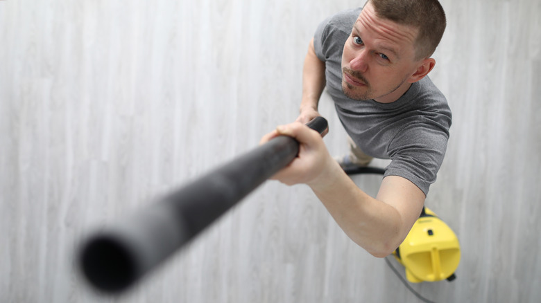 Person trying to vacuum ceiling