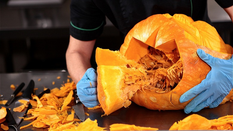 Person removing top of pumpkin