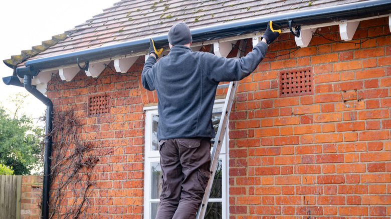 Man on a ladder cleaning the gutters