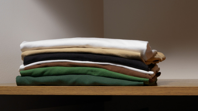 neatly folded T-shirts on a wood shelf