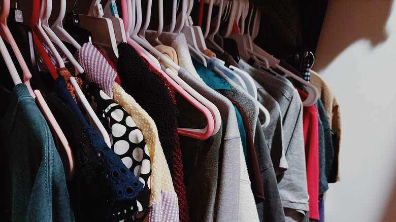 A bunch of shirts and tops haphazardly hung in a closet