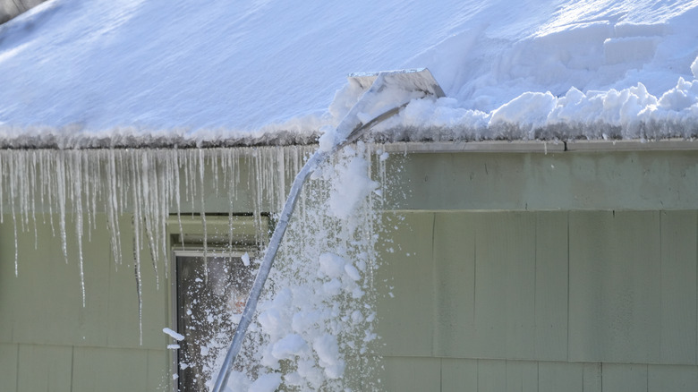 Clearing snow off a roof with a roof rake