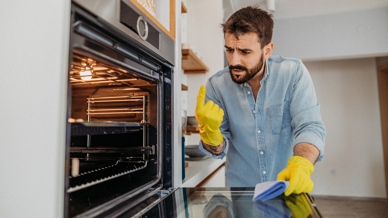 man cleans inside of his oven