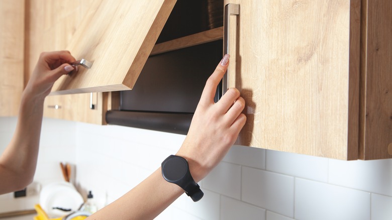 Person opening kitchen cabinet