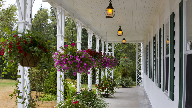 A long white porch decorated with hanging flower baskets