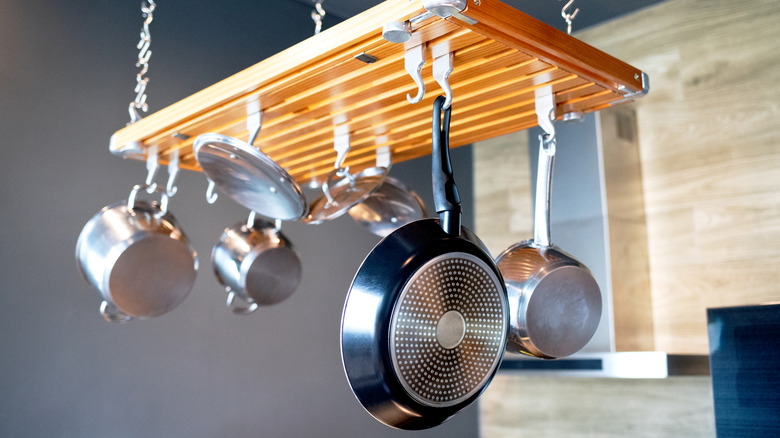 Close up of a hanging wooden pot rack holding cookware