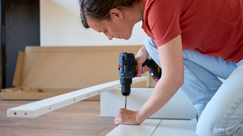 person using cordless drill to assemble furniture