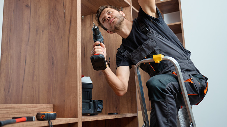 person on step ladder doing home project