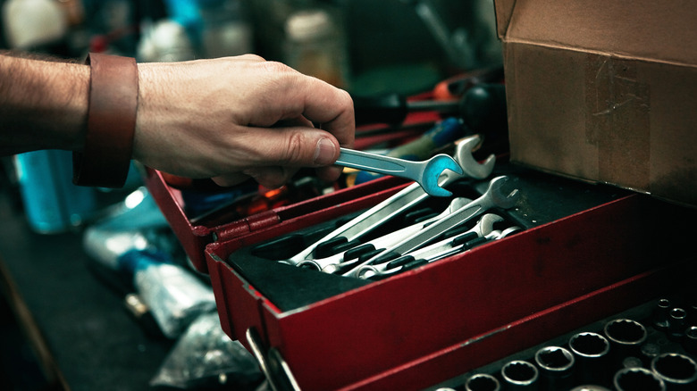 A man reaching into a toolbox and pulling out a wrench