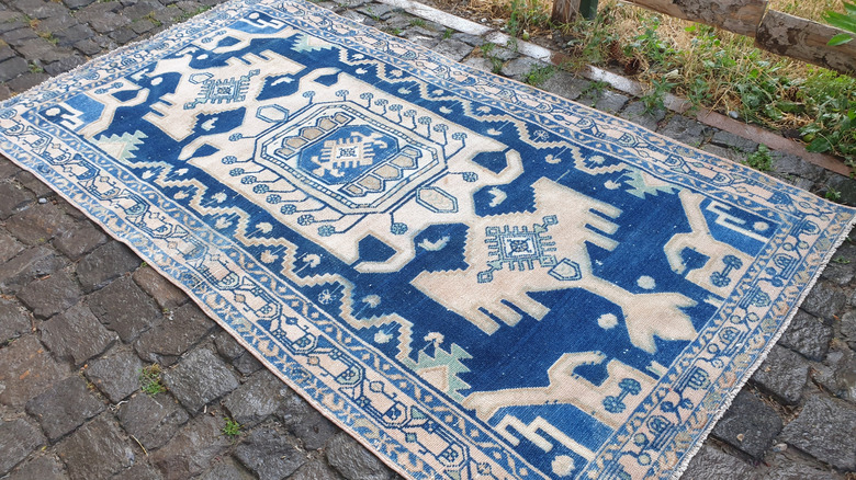 A vintage handmade blue Oushak rug on the ground outdoors