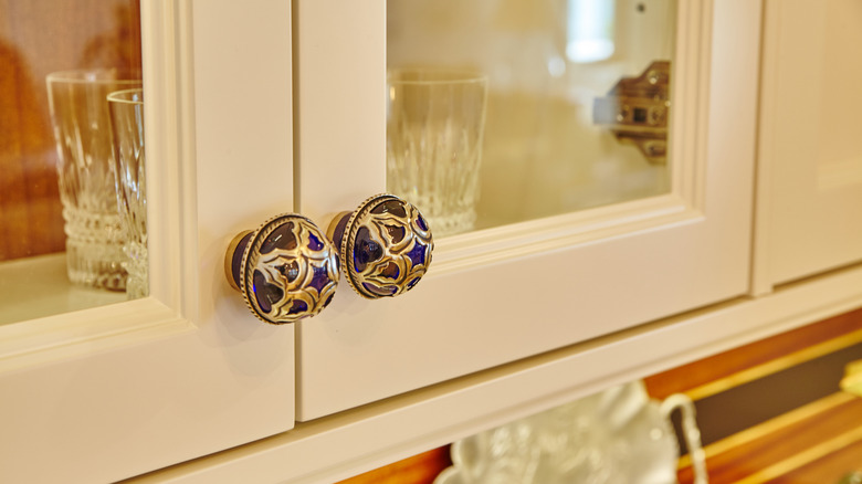 A blue kitchen cabinet knob with brass etched detailing