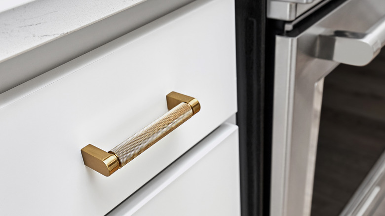 A handle with knurled details on a white kitchen drawer