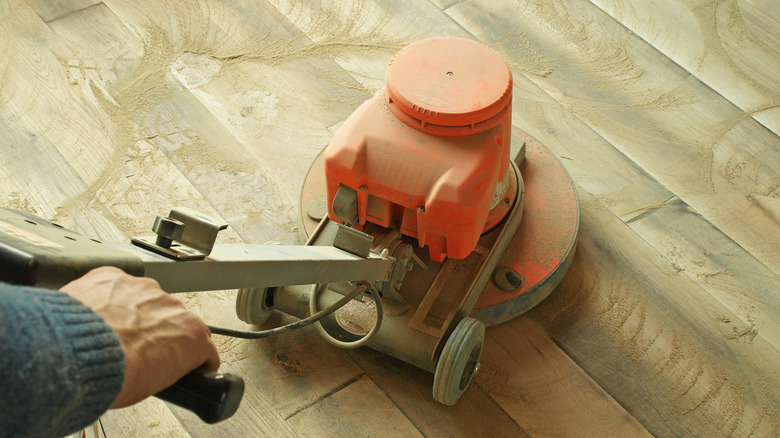 person refinishing hardwood floor