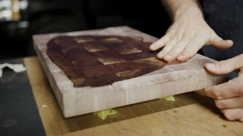 Hands applying oil on a wooden cutting board