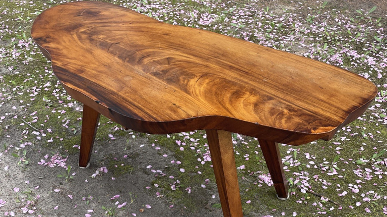 A coffee table with a curved, organic shape made of reddish-brown koa wood