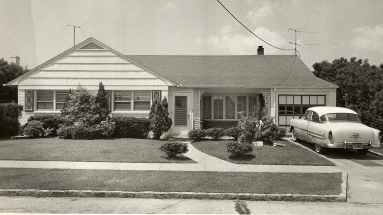 Black and white image of a 1900s house with vintage car