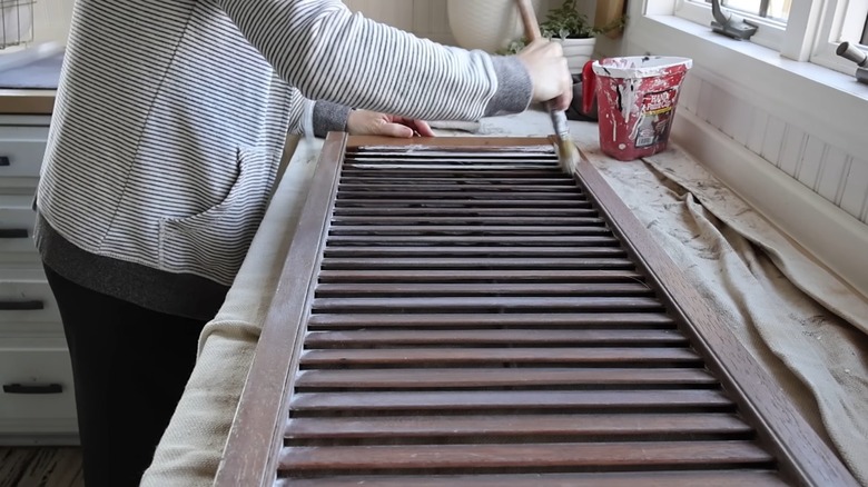 Woman painting brown window shutters