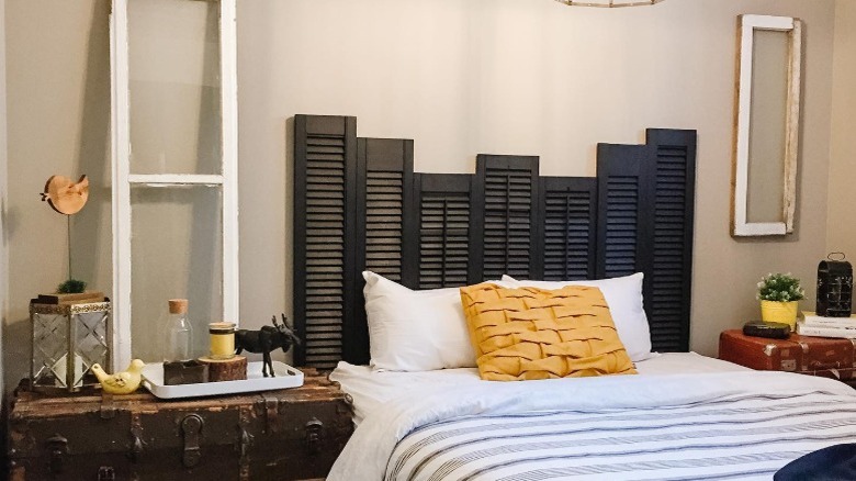 Bed with headboard made from black-painted window shutters.