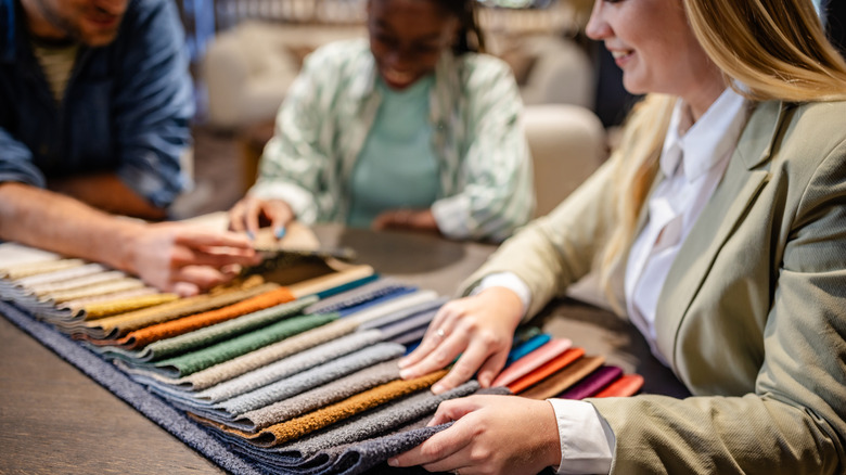 Three people sitting around a table looking at fabric swatches