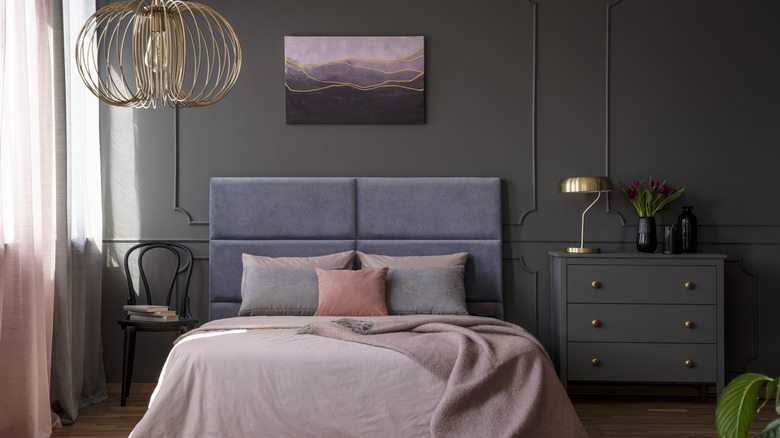 Bedroom with grey walls and dresser, bed, and textured blue headboard.