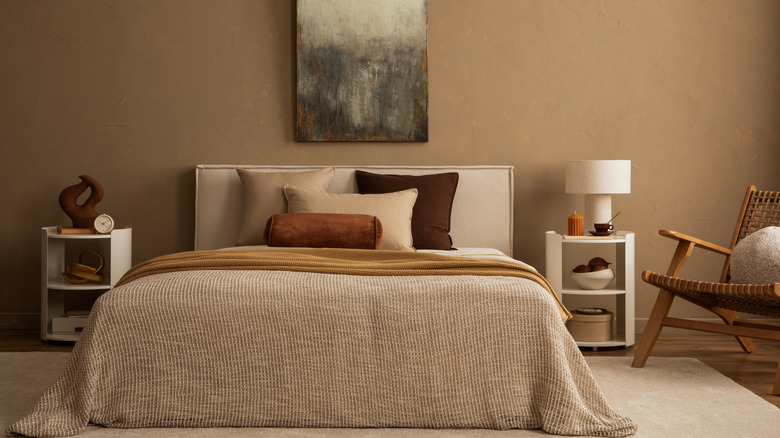 A warm-toned bedroom with soft brown walls and a beige bedspread