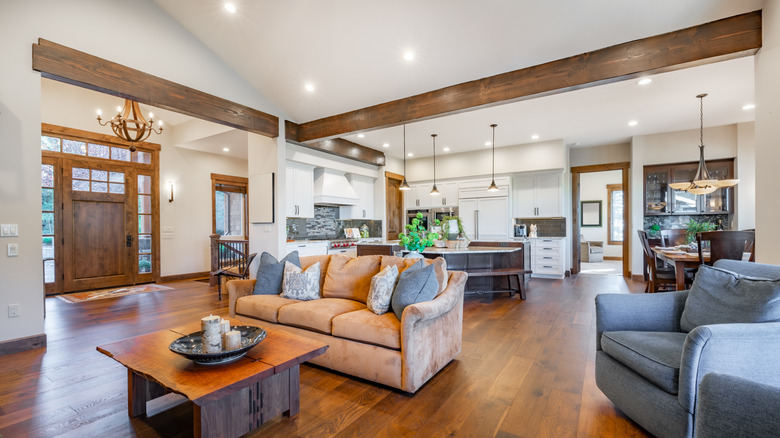 Living room with white walls and wooden beams on ceiling.