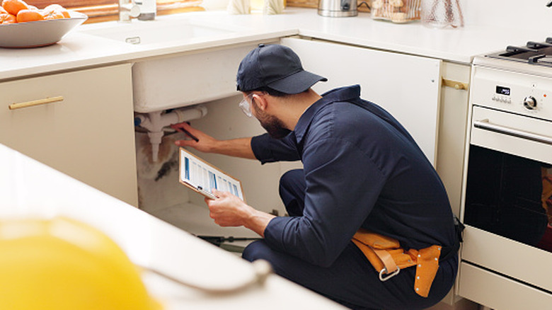 Plumber checking the pipes under a sink