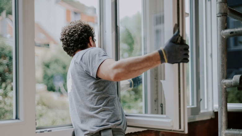 A professional man installing a new window frame in a home