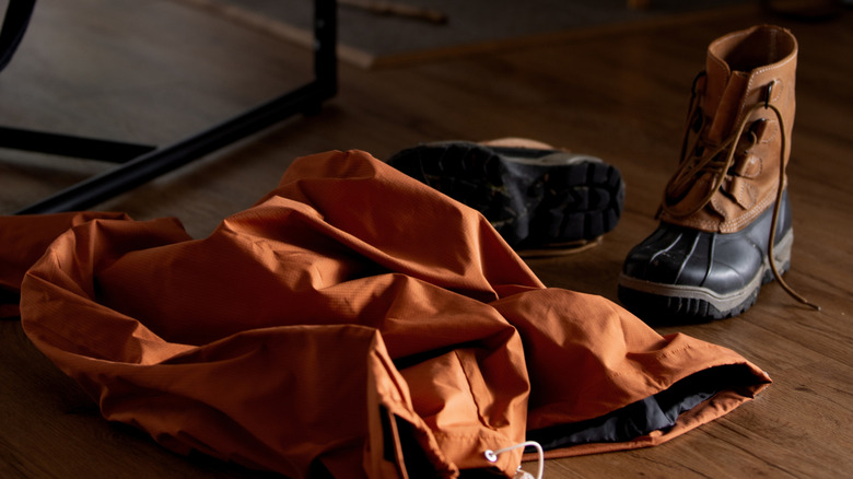 A winter jacket and boots on a wood floor