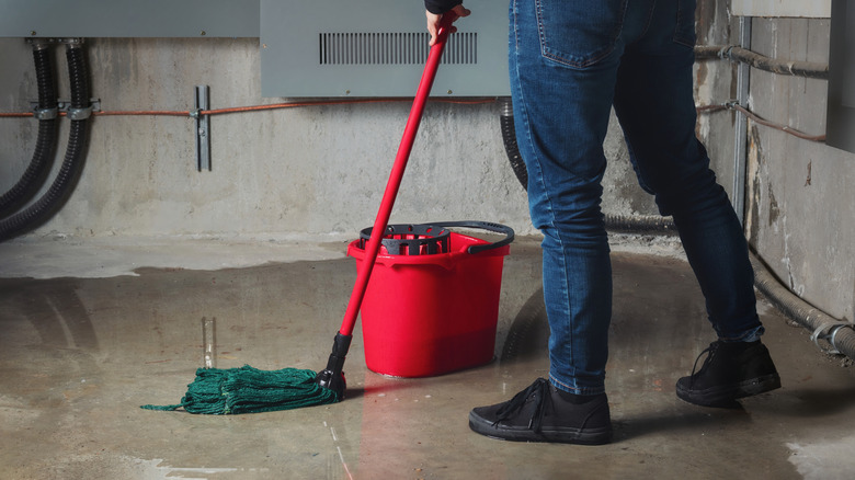 A person cleaning a concrete floor with a mop
