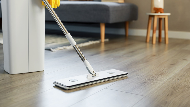 A person cleaning wood-look laminate flooring in a living room